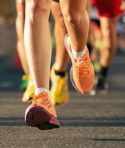 Close up of women's running shoes during a road race with other runner's shoes in the background